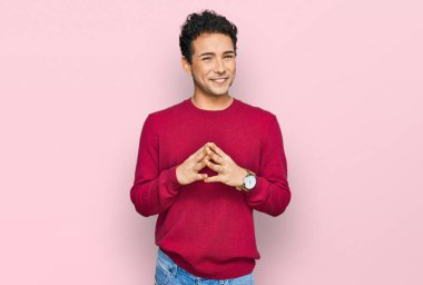 Genç, yakışıklı, sıradan kıyafetler giyen, el ele tutuşan, gülümseyen, gevşemiş ve neşeli bir adam. Başarı ve iyimserlik 