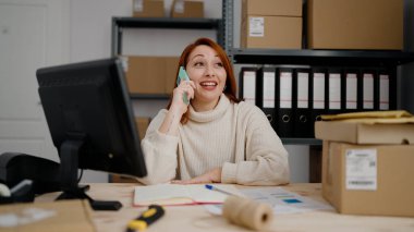 Genç kızıl saçlı kadın iş kadını ofisteki akıllı telefondan konuşuyor.