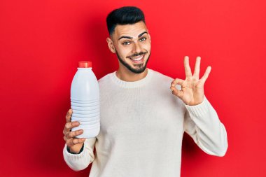 Sakallı, elinde litrelik süt şişesi olan genç İspanyol adam parmaklarıyla imza atıyor, gülümseyerek mükemmel bir sembol oluşturuyor. 