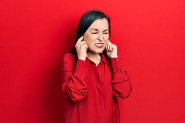 Orta yaşlı İspanyol kadın gündelik kıyafetler giyip yüksek sesli müzik sesi için kulaklarını parmaklarıyla kapatıyor. sağır kavramı. 