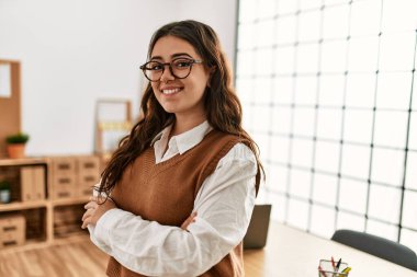 İş kadını kollarını kavuşturup mutlu bir şekilde gülümsüyor..