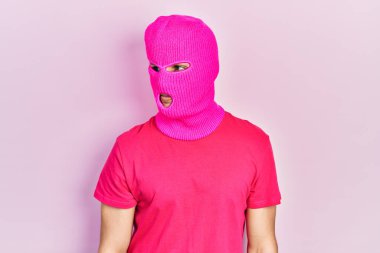 Modern boyalı saçlı, pembe kar maskeli genç bir adam yan tarafa bakıyor, rahat bir görünüm takınıyor ve kendine güvenen bir gülümseme takınıyor.. 