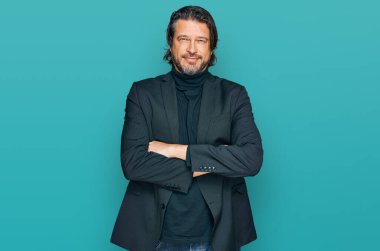 Orta yaşlı, iş kıyafetleri giyen, kollarını kavuşturup kameraya gülümseyen yakışıklı bir adam. pozitif kişi. 