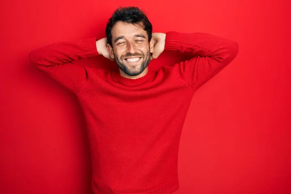 髭を生やしたハンサムな男は カジュアルな赤いセーターを着てリラックスしてストレッチ 腕と手の後ろに頭と首の笑顔幸せ — ストック写真