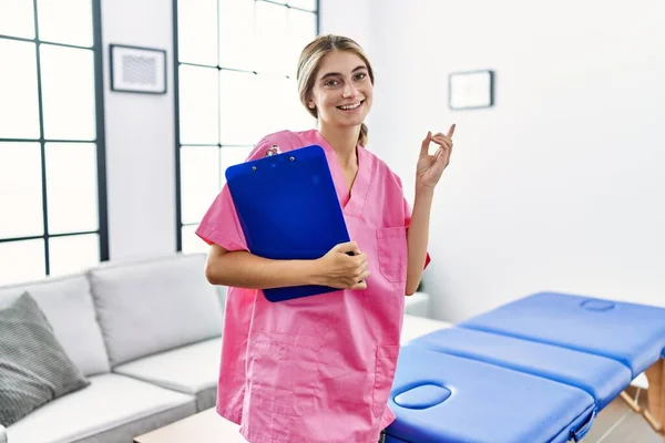 Νεαρή Φυσιοθεραπεύτρια Που Εργάζεται Στο Σπίτι Χαμογελώντας Χαρούμενη Δείχνοντας Χέρι — Φωτογραφία Αρχείου