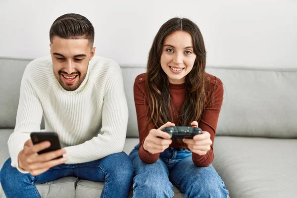 Young Hispanic Couple Playing Video Game Using Smartphone Home — Stock Photo, Image