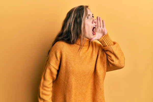 若いブロンドの女性はカジュアルな服を着て大声で叫び 口の中で手で横に大声で叫ぶ コミュニケーションの概念 — ストック写真