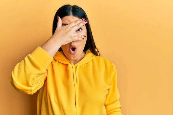 Hermosa Mujer Morena Vistiendo Sudadera Casual Asomándose Shock Cubriendo Cara — Foto de Stock