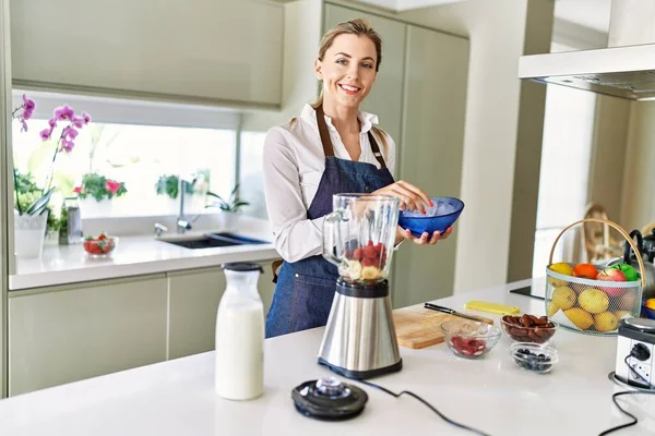 Genç Sarışın Kadın Mutfaktaki Blendere Buz Dökerek Gülümsüyor — Stok fotoğraf
