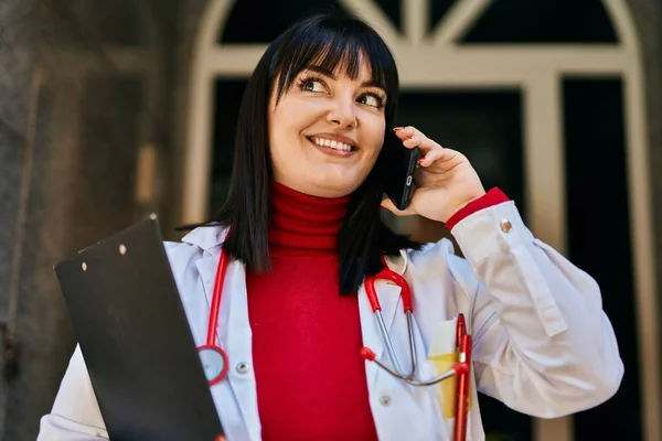 Mujer Morena Joven Vistiendo Uniforme Médico Hablando Por Teléfono Entrada —  Fotos de Stock