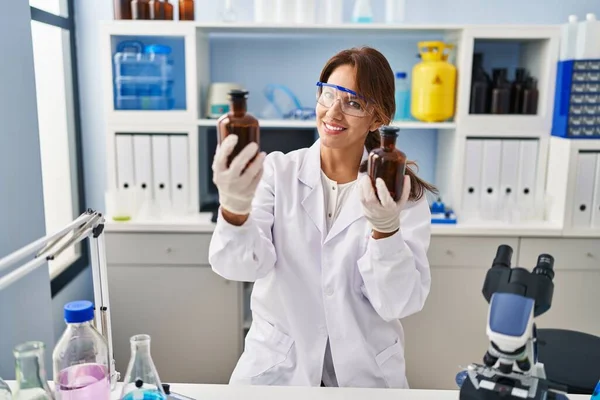 Jovem Latina Vestindo Cientista Uniforme Segurando Garrafas Laboratório — Fotografia de Stock