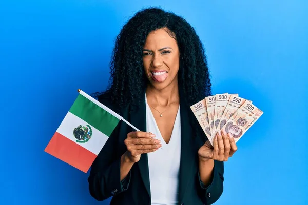 中世のアフリカ系アメリカ人女性がメキシコの国旗とメキシコペソの紙幣を持っていて 面白い表現で幸せに舌を突き出している — ストック写真