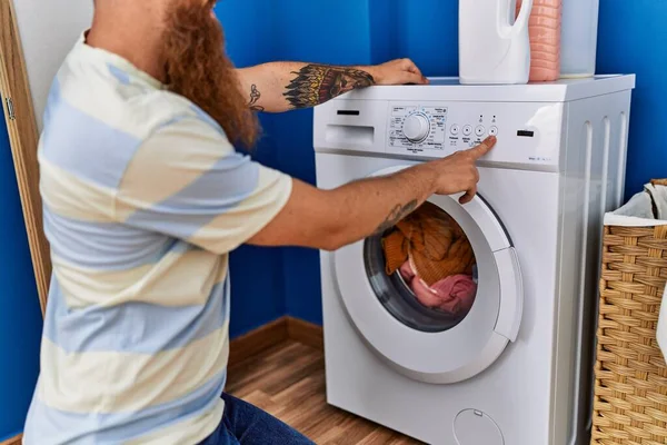 年轻的红头发男子在洗衣房打开洗衣机 — 图库照片