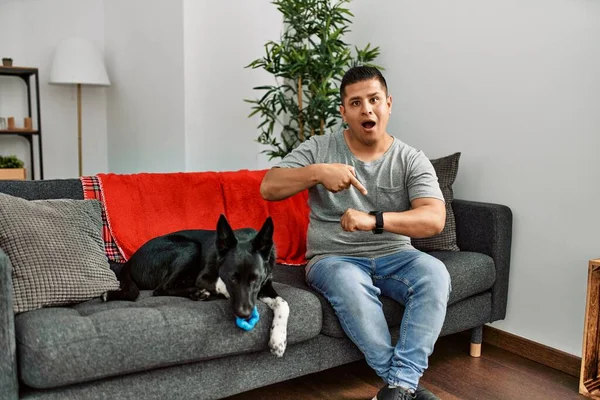 Jovem Latino Homem Cão Sentado Sofá Casa Com Pressa Apontando — Fotografia de Stock