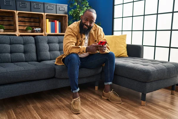 아프리카 미국인 스마트폰을 사용하여 집에서 소파에 — 스톡 사진