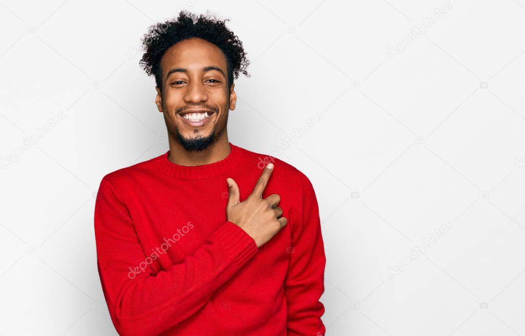 Young african american man with beard wearing casual winter sweater cheerful with a smile on face pointing with hand and finger up to the side with happy and natural expression 