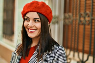 Genç İspanyol kadın gülümseyerek şehirde mutlu mesut dikiliyor..