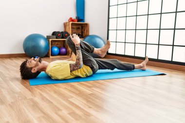 Genç İspanyol adam gülümsüyor spor merkezinde esniyor..