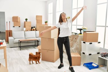 Genç İspanyol kadın yeni evinde köpekle durduğundan emin bir şekilde gülümsüyor.