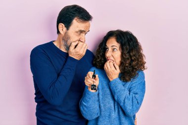Orta yaşlı bir çift İspanyol kadın ve ellerinde yeni evin anahtarları olan gergin ve gergin görünen elleri ağızlarında çivi yiyen bir adam. anksiyete. 