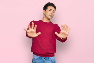 Rahat kıyafetler giyen genç yakışıklı, avuç içi hareketlerini durduruyor, kızgın ve hayal kırıklığına uğramış bir ifade takınıyor. 