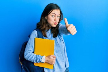 Sırt çantası takan esmer, genç bir bayan öğrenci. Komik yüzlü, güzel hareketler yapıyor. Ağzı havayla şişer, havayı yakalar.. 