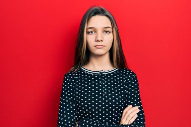 Genç esmer kız sıradan bir süveter giyiyor şüpheci ve gergin, yüzünde çapraz kollu tasvip etmeyen bir ifade var. negatif kişi. 