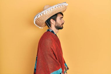 Meksika şapkası tutan genç İspanyol adam, yan yan yan bakıyor, rahat poz veriyor, kendine güvenen bir gülümsemesi var.. 