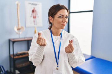 Genç esmer kadın ağrı kesici kliniğinde çalışıyor. Elleriyle para hareketi yapıyor. Maaş istiyor. 