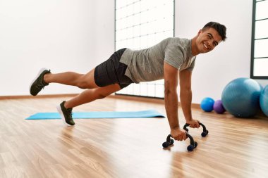 Genç İspanyol adam gülümsüyor spor merkezinde kendine güvenen karın kasları egzersizi yapıyor.