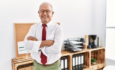 Üst düzey bir iş adamı, kollarını kavuşturup ofiste el kol geziyor.