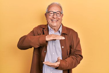 Gri saçlı, günlük ceket giyen ve elleri büyük ve büyük boy işareti gösteren gözlüklü yaşlı adam, ölçü sembolü. Kameraya bakıp gülümsüyor. ölçüm kavramı. 