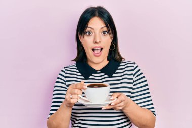 Bir fincan kahve içen genç İspanyol kadın şaşkınlık ve şaşkınlık dolu bir ifade, korku ve heyecanlı bir yüz ifadesiyle şoka girdi.. 