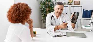 Doktor üniforması giyen orta yaşlı bir adam ve kadın klinikte tıbbi danışmanlık yapıyorlar.