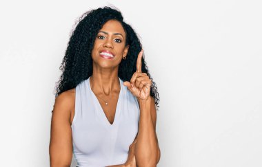 Orta yaşlı Afro-Amerikalı kadın kolsuz gömlekli, kolsuz, yüzünde kocaman bir gülümseme, elleri ve parmakları kameraya bakıyor.. 