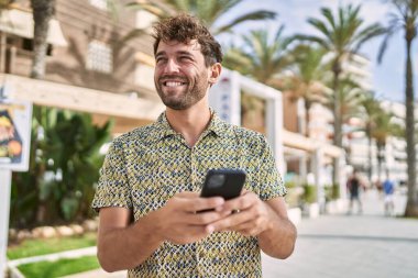 Sokakta akıllı telefon kullanan, kendine güvenen genç bir İspanyol.