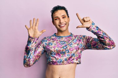 Makyaj giysileri giymiş yakışıklı bir adam yedi numarayı gösterip işaret ederken kendine güvenen ve mutlu bir şekilde gülümsüyor.. 