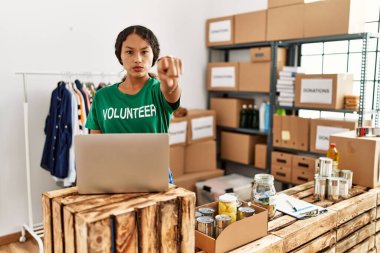 Güzel İspanyol kadın gönüllü tişört giyiyor. Bilgisayarla çalışıyor. Kamerayı işaret ediyor. 