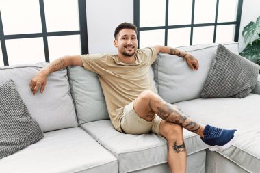 Genç İspanyol adam evde kendinden emin gülümsüyor.