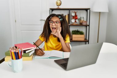 Genç Afro-Amerikalı kız evde ödevini yapıyor bağırıyor ve ağızdan ağıza bağırıyor. iletişim konsepti. 