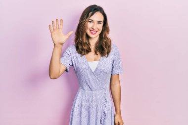 Gündelik kıyafetler giyen genç İspanyol kız beş numarayı gösterip işaret ederken kendinden emin ve mutlu gülümsüyor.. 