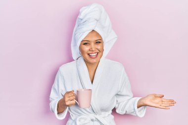 Bornoz giyen genç İspanyol kız bir fincan kahve içerek başarıyı mutlu bir gülümsemeyle kutluyor ve kazanan el kaldırarak ifade ediyor. 