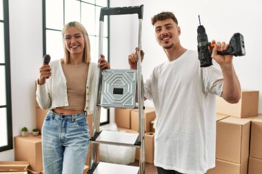 Genç beyaz çift mutlu bir şekilde gülümsüyor işçi merdivenlerini tutuyor ve yeni evlerinde talim yapıyor..