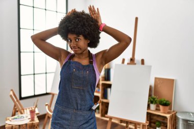 Sanat stüdyosunda afro saçlı, el hareketleriyle tavşan kulağı hareketi yapan, kuşkucu ve alaycı genç Afrikalı Amerikalı bir kadın. Paskalya tavşanı konsepti. 