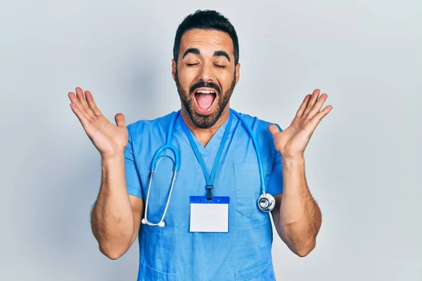 Homem Hispânico Bonito Com Barba Vestindo Uniforme Médico Celebrando Louco — Fotografia de Stock