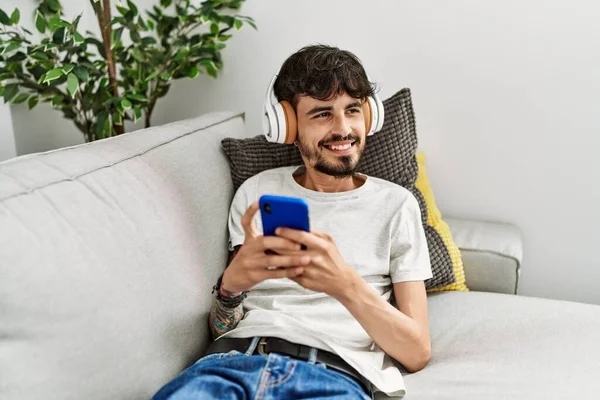 Jovem Hispânico Usando Smartphone Fones Ouvido Deitados Sofá Casa — Fotografia de Stock