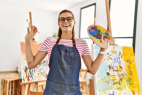 Mujer Joven Sonriendo Confiada Sosteniendo Pincel Paleta Estudio Arte — Foto de Stock