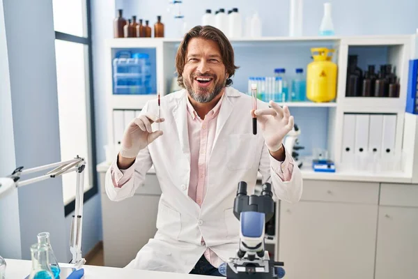 ハンサムな中年男保持血サンプルで生物学研究所笑顔と笑いハードアウト大声でので面白いクレイジー冗談 — ストック写真