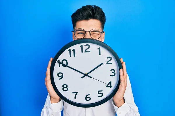 Giovane Uomo Ispanico Tenendo Grande Orologio Sul Viso Ammiccando Guardando — Foto Stock