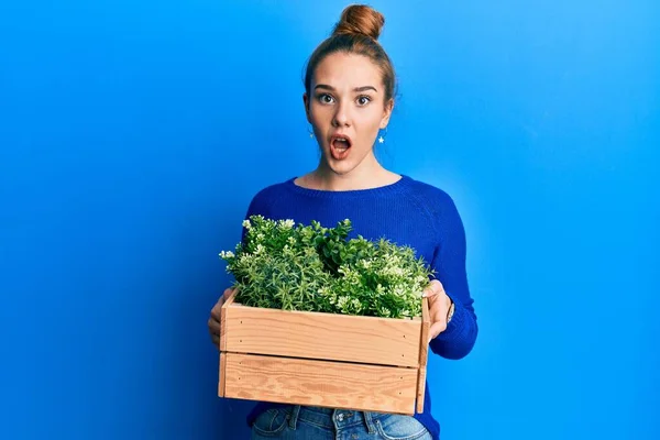 Ung Blond Kvinna Håller Trä Växt Kruka Rädd Och Chockad — Stockfoto